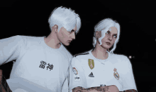 a man and a woman are standing next to each other wearing adidas shirts