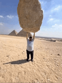 a man is holding a large rock over his head