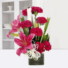 a vase filled with pink lilies and red carnations is sitting on a table