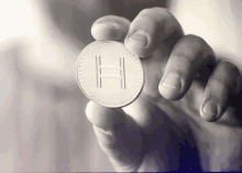 person holding a coin with the letter h on it