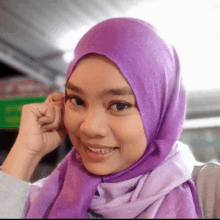 a woman wearing a purple scarf and hijab smiles