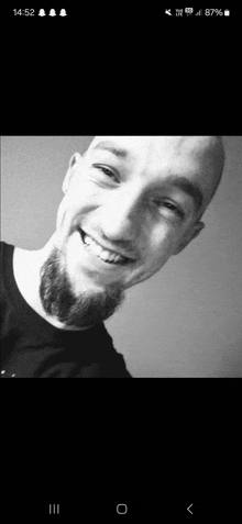 a black and white photo of a man with a beard smiling for the camera .