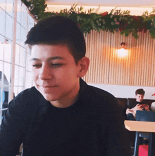 a boy in a black shirt is sitting at a table in a restaurant