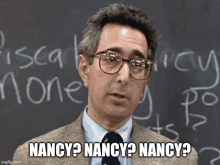 a man wearing glasses stands in front of a blackboard with the words nancy nancy nancy on it