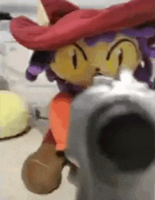 a stuffed animal wearing a red hat and purple hair is pointing a gun at the camera .