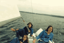 a group of people on a sailboat with one wearing a blue jacket