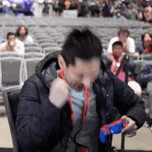 a man with a lanyard around his neck is holding a blue controller