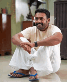 a man sits on the floor wearing flip flops