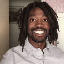 a man with dreadlocks and a beard wearing a white shirt