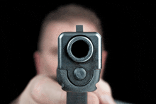 a man holds a gun in front of his face