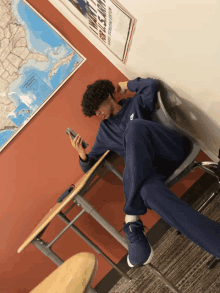 a boy sits at a desk with his legs crossed in front of a map of the united states of america