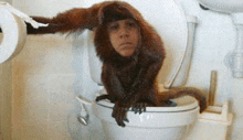 a monkey is sitting on top of a toilet with a person 's face on it .