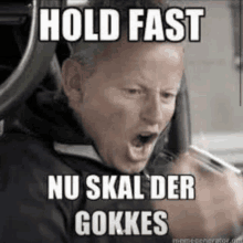 a man is driving a car and making a funny face with the words hold fast nu skal der gokkes .