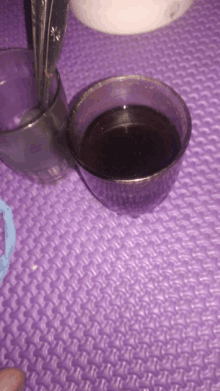 a purple mat with a bowl of liquid and a spoon on it