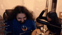 a man wearing a shirt that says streamer is being slapped by a woman in front of a microphone