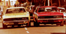 a yellow charger and a red charger are parked on the side of the road