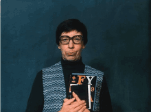 a man wearing glasses holds a book titled fy 9