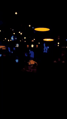 a blurry picture of a dark room with a lot of lights and people .