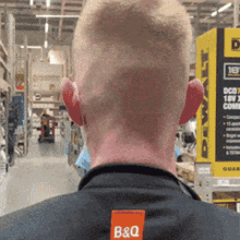 a man wearing a black shirt with an orange b & q logo on the back