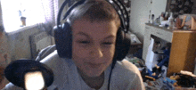 a young boy wearing headphones looks at the camera and smiles