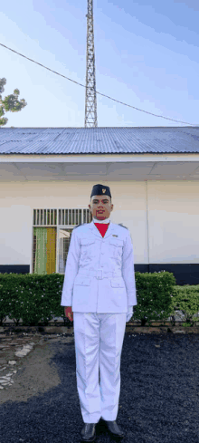 a man in a white uniform stands in front of a house