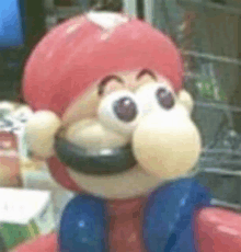 a close up of a toy mario with big eyes and a red hat .