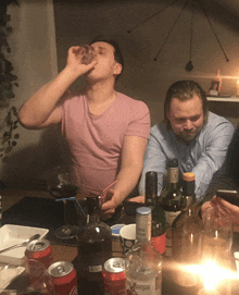 a man drinking from a glass next to a morgan bottle