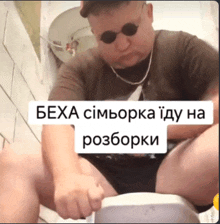 a man wearing sunglasses sits on a toilet with a caption in a foreign language that says bexa