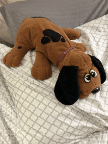 a stuffed dog laying on a bed with a collar that says ' snoopy ' on it