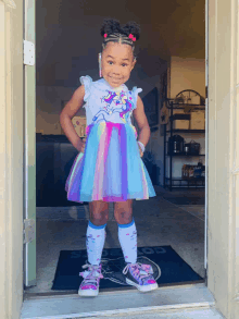 a little girl wearing a unicorn dress and socks stands in front of a door