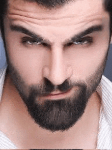 a close up of a man 's face with a beard and a white shirt .