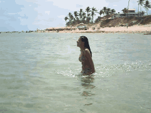 a woman in a bikini is standing in a body of water