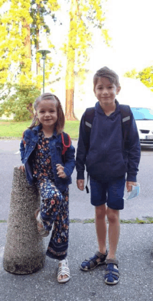 a boy and a girl standing next to each other on a sidewalk