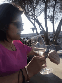 a woman in a pink shirt holds a glass of wine in front of a building that says steaks and ribs