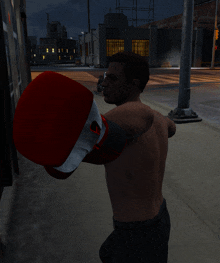 a man without a shirt is wearing a red boxing glove with a white logo on it