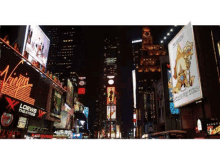 a busy city street at night with a loews theatre sign in the foreground