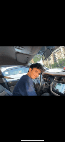 a man is sitting in the driver 's seat of a car with his head on the steering wheel