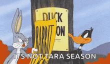 bugs bunny and daffy duck are standing next to a sign that says `` duck on rabbit on '' .