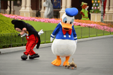 mickey mouse and donald duck are walking down a street with ducklings