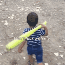 a young boy is carrying a yellow baseball bat with the words " don 't fuck with me " written on it