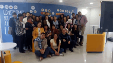 a group of people are posing for a picture in front of a wall that says construyamos