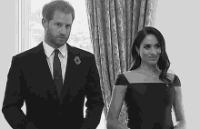 a black and white photo of a man in a suit and tie and a woman in a dress .