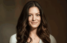 a woman with long dark hair and a white shirt is smiling