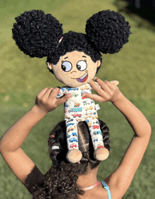 a girl holds a stuffed doll with cars on it