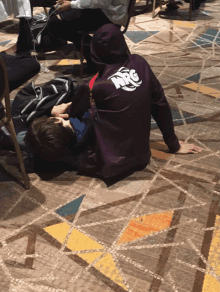 a person wearing a purple nrg hoodie laying on the floor