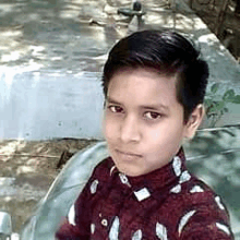 a young boy in a red shirt is taking a selfie while sitting on a bench .