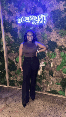 a woman is standing in front of a blue sign that says bluprint summit