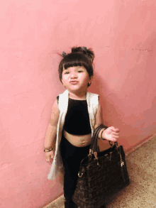 a little girl wearing a black crop top and a white vest is holding a purse