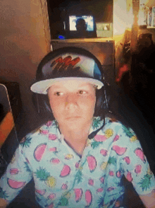 a boy wearing headphones and a hat with the letter m on it looks at the camera