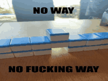 a stack of blue and white tiles on a wooden table with the words no way and no fucking way below them